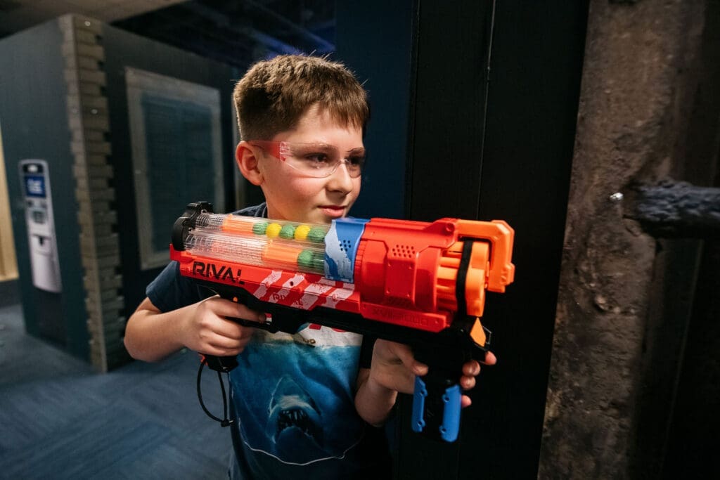 "Thrilling Nerf combat game with players dodging and shooting foam darts in an outdoor arena."