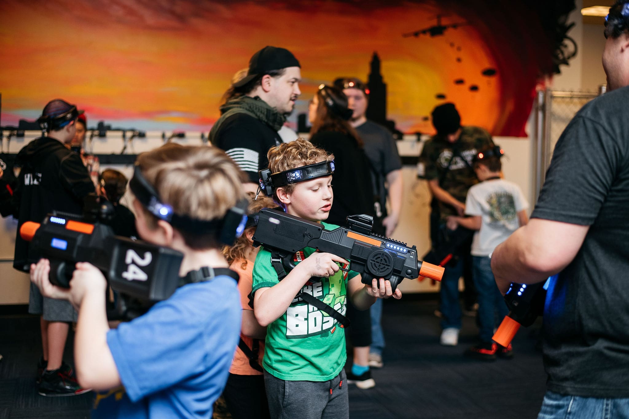"Action-packed Nerf party event with kids and adults battling with foam dart blasters in an indoor setting."